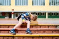 Portrait of Beautiful school boy looking very happy outdoors at the day time. Sitting on the steps with books and a large school Royalty Free Stock Photo