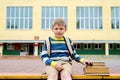 Portrait of Beautiful school boy looking very happy outdoors at the day time. Sitting on the steps with books and a large school Royalty Free Stock Photo