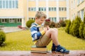 Portrait of Beautiful school boy looking very happy outdoors at day time. Sitting on the steps with books and a large Royalty Free Stock Photo