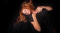 Portrait of a beautiful seductive sensual, young sexy redhead, a beautiful ginger woman with long curly red hair in black cloth, Royalty Free Stock Photo