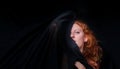 Portrait of a beautiful seductive sensual, young sexy redhead, a beautiful ginger woman with long curly red hair with black cloth Royalty Free Stock Photo