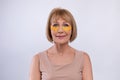 Portrait of beautiful senior woman with golden patches under her eyes looking at camera on light studio background Royalty Free Stock Photo