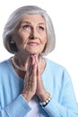 Portrait of beautiful senior woman in light blue blouse praying Royalty Free Stock Photo