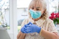 Portrait of beautiful senior woman wearing protective mask and gloves having video chat on laptop at home Royalty Free Stock Photo