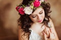 Portrait of beautiful sensual brunette girl in a white lace dress, with a wreath of flowers on his head, on a brown background in Royalty Free Stock Photo