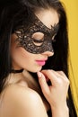 Portrait of beautiful sensual woman in black lace mask on yellow background. girl in venetian mask