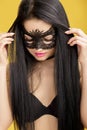 Portrait of beautiful sensual woman in black lace mask on yellow background. girl in venetian mask