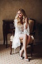 Sensuality blondie bride sitting on chair in luxury interior.