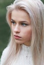 Portrait of a beautiful serious blonde girl in a white knitted sweater. Close-up profile Royalty Free Stock Photo