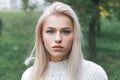 Portrait of a beautiful serious blonde girl in a white knitted sweater. Royalty Free Stock Photo