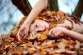 Portrait of beautiful sexy lovely young redhead girl lying on autumn leaves, covered with red and orange autumnal leaves Royalty Free Stock Photo