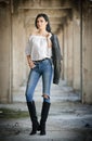 Portrait of beautiful young woman with modern outfit, leather jacket, jeans, white blouse and black boots Royalty Free Stock Photo