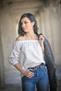 Portrait of beautiful young woman with modern outfit, leather jacket, jeans, white blouse and black boots Royalty Free Stock Photo