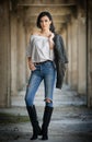 Portrait of beautiful young woman with modern outfit, leather jacket, jeans, white blouse and black boots Royalty Free Stock Photo