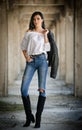 Portrait of beautiful young woman with modern outfit, leather jacket, jeans, white blouse and black boots Royalty Free Stock Photo