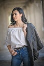 Portrait of beautiful young woman with modern outfit, leather jacket, jeans, white blouse and black boots Royalty Free Stock Photo