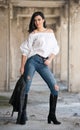 Portrait of beautiful young woman with modern outfit, leather jacket, jeans, white blouse and black boots Royalty Free Stock Photo