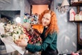 Portrait of beautiful shop assistant taking two flower bouquets in flower shop