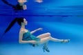 Portrait of beautiful slim stylish brunette in blue dress and heels shoes underwater