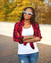 Portrait beautiful smiling african woman wearing a sunglasses, red checkered shirt in sunny autumn Royalty Free Stock Photo