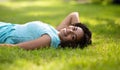 Portrait of beautiful smiling black woman lying on green grass at park Royalty Free Stock Photo