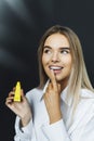 Portrait beautiful blonde woman with straight hair isolated on dark background in white shirt, holding hand to her face Royalty Free Stock Photo