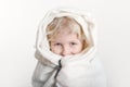 Portrait of beautiful smiling Caucasian girl wrapped in white blanket. Happy preschool child with blue eyes covered with warm