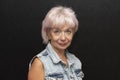 Portrait of a beautiful smiling elderly woman 60-65 years old in a denim jacket on a black background. Royalty Free Stock Photo