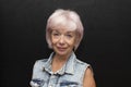 Portrait of a beautiful smiling elderly woman 60-65 years old in a denim jacket on a black background. Royalty Free Stock Photo