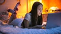 Portrait of beautiful smiling girl lying on bed and using laptop Royalty Free Stock Photo