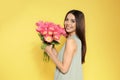 Portrait of beautiful smiling girl with spring tulips on yellow background. Royalty Free Stock Photo