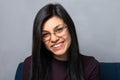 Portrait of a beautiful, smiling, happy, brunette woman, wearing glasses, on a gray background. Looks at the camera. Close-up. Royalty Free Stock Photo