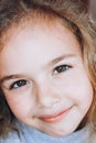 Portrait of a beautiful smiling little girl. Pretty child with blond curly hair looking to camera close-up Royalty Free Stock Photo