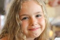 Portrait of a beautiful smiling little girl. Pretty child with blond curly hair looking to camera close-up Royalty Free Stock Photo