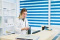 Portrait of a beautiful smiling nurse at desk station while talking on the phone and complete a medical information form Royalty Free Stock Photo