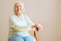 Portrait of a beautiful smiling senior woman with walking cane on light background at home Royalty Free Stock Photo