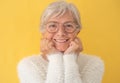 Portrait of beautiful smiling senior woman white-haired looking at camera wearing eyeglasses, isolated on yellow background Royalty Free Stock Photo