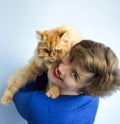 Portrait of beautiful smiling short haired 30 years old woman in blue dress playing with ginger red furry persian cat. Domestic Royalty Free Stock Photo