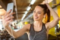 Portrait of beautiful smiling sporty girl with earphone taking a selfie using smart phone in the gym Royalty Free Stock Photo