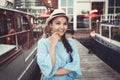 Portrait of beautiful smiling white Caucasian brunette girl on boat yacht pier quay, in blue dress and straw hat Royalty Free Stock Photo