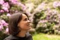 Portrait of a beautiful smiling woman in a black t-shirt looking up against the background of a flowering rhododendron bush Royalty Free Stock Photo