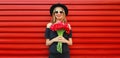 Portrait of beautiful smiling woman with bouquet of red rose flowers in black round hat on background Royalty Free Stock Photo