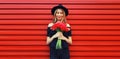 Portrait of beautiful smiling woman with bouquet of red rose flowers in black round hat on background Royalty Free Stock Photo