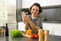 Portrait of beautiful smiling woman, cooking food at home, looking at smartphone, looking for healthy vegetarian recipe