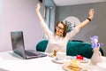 Portrait of beautiful smiling woman in glasses in winning pose sitting in a cafe with laptop indoors Royalty Free Stock Photo