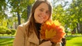 Portrait of beautiful smiling woman holding bunch of yellow maple trees in autumn park. Beauty in nature, fall in the city, happy Royalty Free Stock Photo