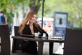 Portrait of beautiful smiling woman sitting in a cafe with laptop outdoor