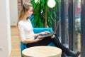 Portrait of beautiful smiling woman sitting on a comfortable chair in a cafe with black laptop. Pretty student doing work with lap Royalty Free Stock Photo