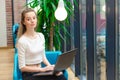 Portrait of beautiful smiling woman sitting on a comfortable chair in a cafe with black laptop. Pretty student doing work with lap Royalty Free Stock Photo