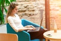 Portrait of beautiful smiling woman sitting on a comfortable chair in a cafe with black laptop. Pretty student doing work with lap Royalty Free Stock Photo